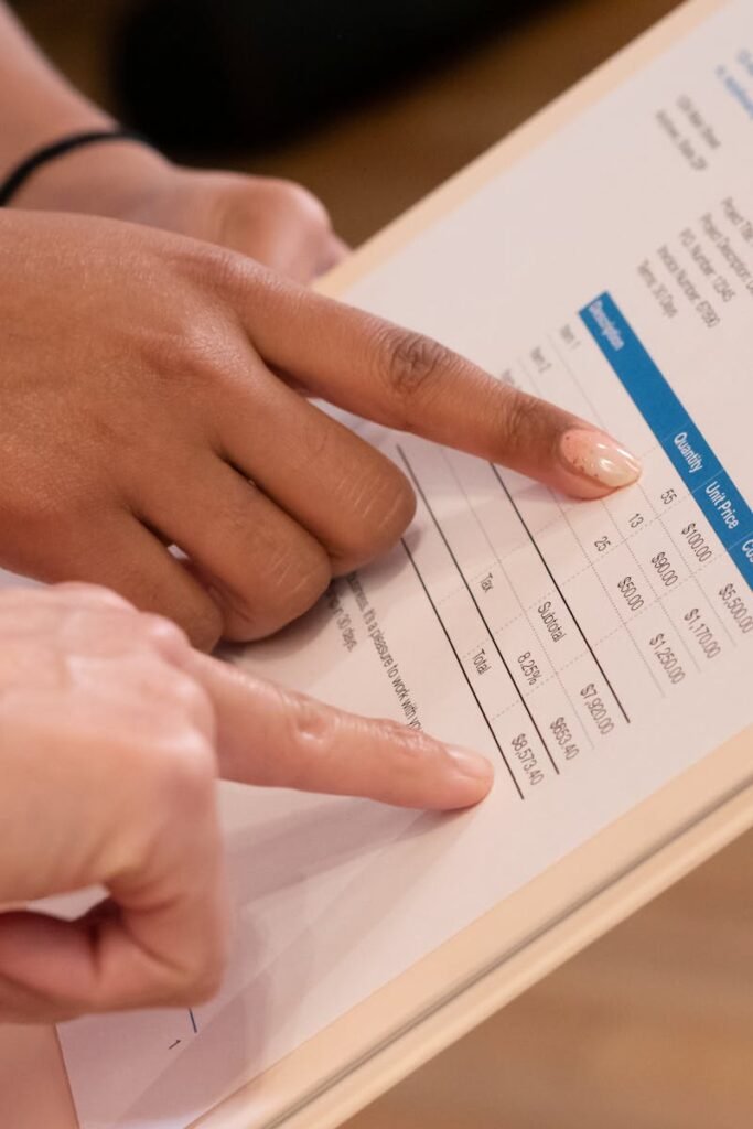 pexels-photo-7688191-7688191 Two people pointing at financial details on a document, highlighting invoice analysis.