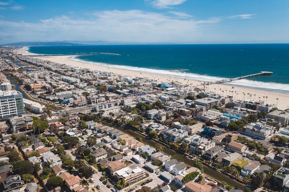 A stunning aerial view of a coastal urban city with a vibrant beach and pier.
