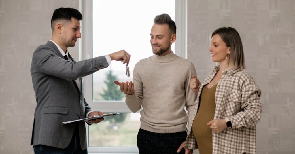 A pregnant woman and her partner receive house keys from a real estate agent indoors.