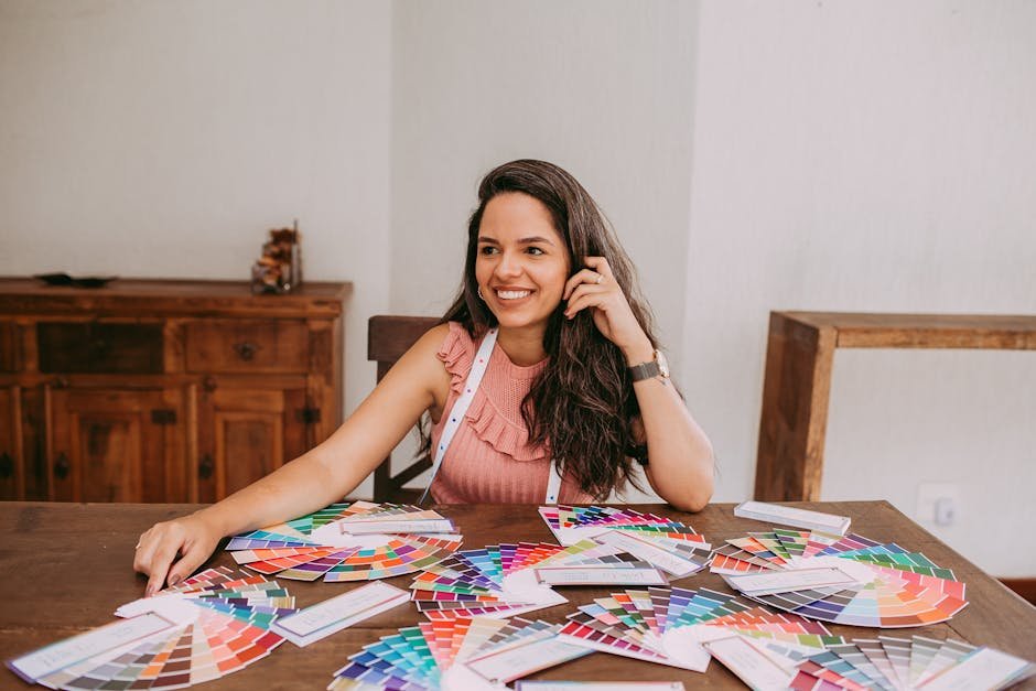 Smiling designer sitting at desk with various color palettes, showcasing creativity and design process.